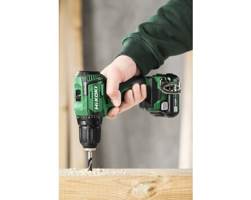 Een persoon boort met een accuboormachine een gat in een houten plank.