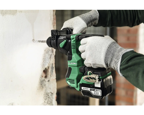 Iemand boort met een accuboormachine een gat in een muur.