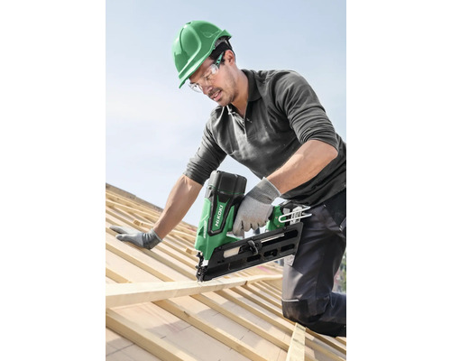 Ambachtsman bevestigt houten lat met een accuspijkerapparaat op een dak