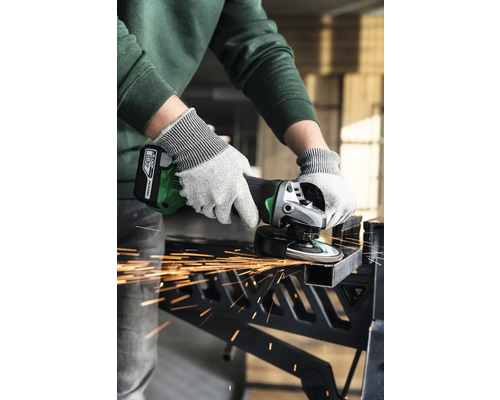 Een persoon gebruikt een accuheggenschaar om een stuk metaal te snijden, waarbij vonken vrijkomen.