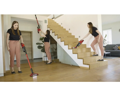 Vrouw gebruikt draadloze stofzuiger in huis op de vloer, het plafond en de trap
