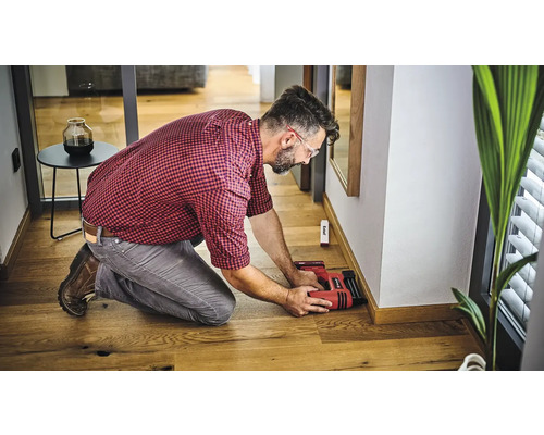 Man bevestigt plinten met een elektrische tacker aan een muur