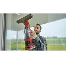 Man maakt ramen schoon met een draadloze ruitenreiniger