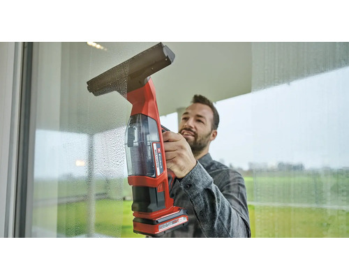 Man maakt ramen schoon met een draadloze ruitenreiniger
