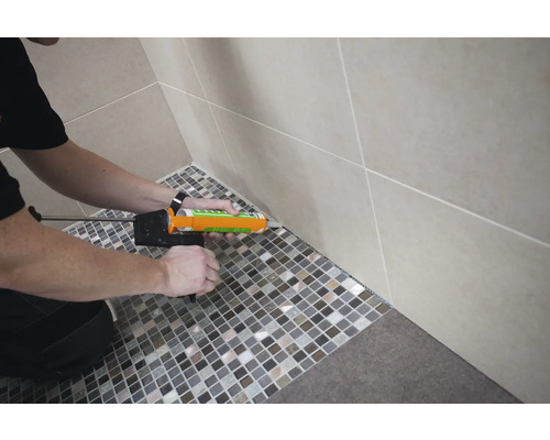 Mozaïektegels voegen in de badkamer met een kitpistool