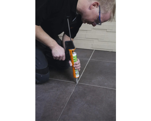 Ambachtsman brengt voegmiddel tussen tegels aan met een voegpistool.