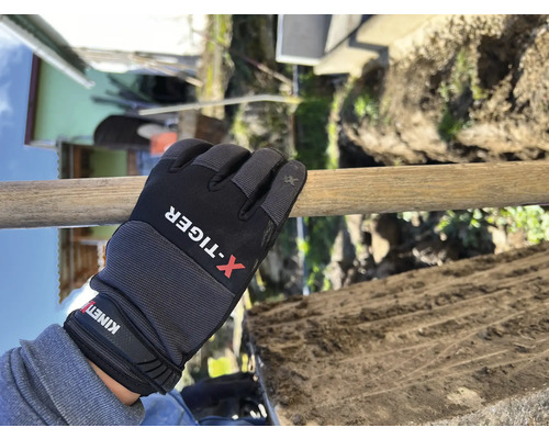 Een hand met werkhandschoen houdt een spade vast tijdens het graven.