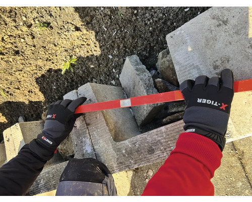 Persoon met handschoenen nivelleert betonstenen met een waterpas