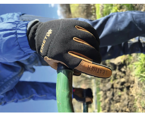 Hand met Kinetix werkhandschoenen op een tuingereedschap