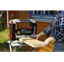 Een man schaaft een houten plank met een Metabo schaafmachine