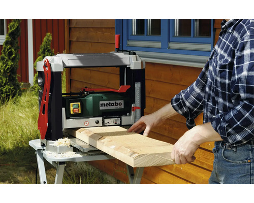 Een man schaaft een houten plank met een Metabo schaafmachine