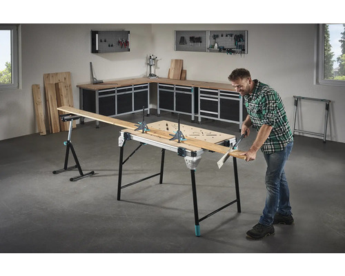 Werkplaatsinrichting met werkbank, houten planken en doe-het-zelver die een plank zaagt