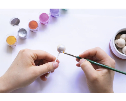 Handen schilderen houten kraal met penseel en verf