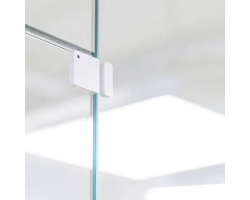 Witte raam- of deurcontactsensor bevestigd op een glazen paneel