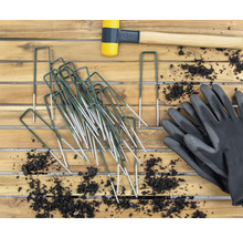 Tuinopname met haringen, rubberen hamer en tuinhandschoenen op houten tafel