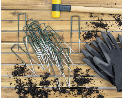 Tuinopname met haringen, rubberen hamer en tuinhandschoenen op houten tafel