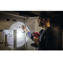 Een man inspecteert een zekeringkast met een Einhell lamp.