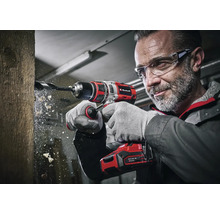 Een man boort met een Einhell accuboormachine een gat in een stuk hout.