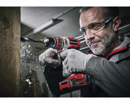 Een man boort met een Einhell accuboormachine een gat in een stuk hout.