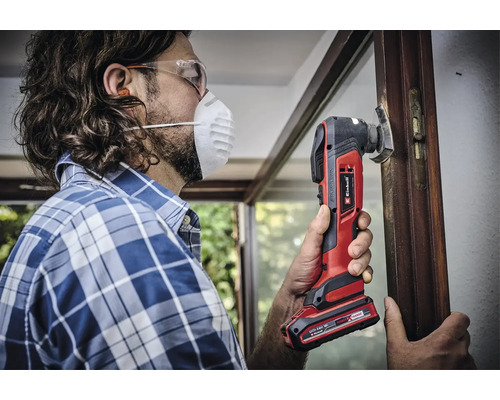 Man werkt met een Einhell multitool aan een raamkozijn