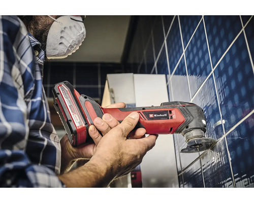 Een man werkt met een Einhell multitool aan tegels.