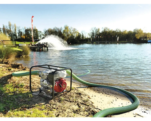 Waterpomp met slang in gebruik aan de oever van een meer