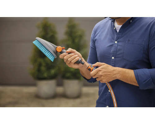 Man sluit wasborstel aan op tuinslang