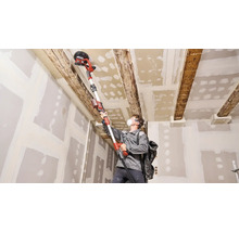 Man schuurt plafond met een plafondschuurmachine in een kamer