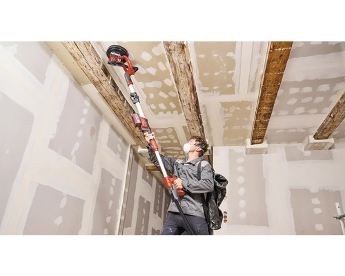 Man schuurt plafond met een plafondschuurmachine in een kamer