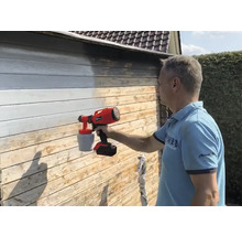 Man schildert houten wand met verfspuitsysteem