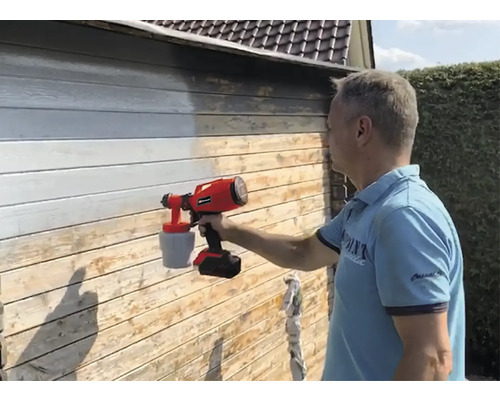 Man schildert houten wand met verfspuitsysteem