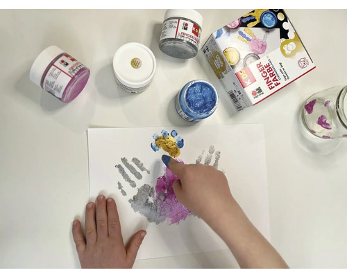 Kind schildert met vingerverf op papier, verschillende verfpotten en een glas staan klaar