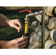 Persoon repareert een tuinslang met isolatietape aan een kraan.