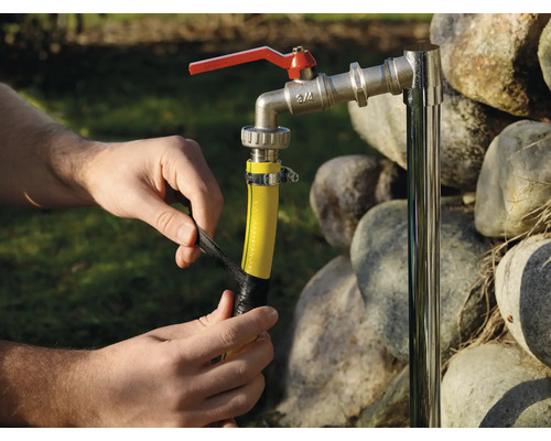 Persoon bevestigt een tuinslang aan een waterkraan met isolatietape.