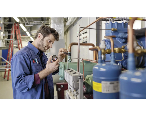 Een man inspecteert een industriële koelinstallatie.