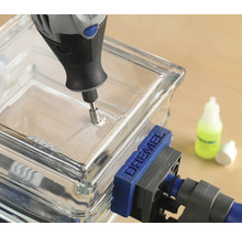 Een glastegel wordt geboord met een multifunctioneel gereedschap, waarbij een klem de tegel fixeert.