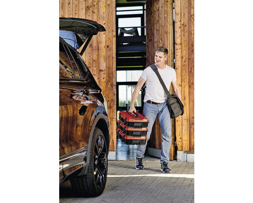 Man draagt drie gereedschapskisten naar de auto