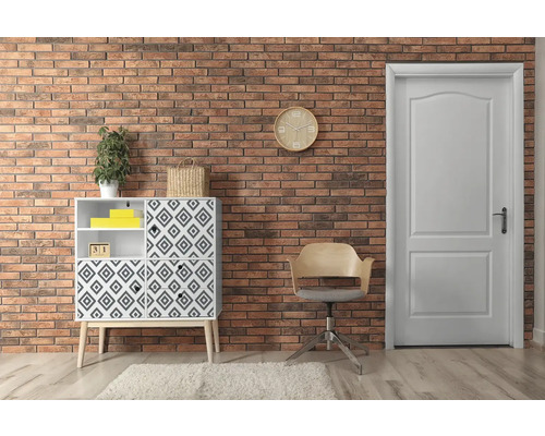 Woonkamer met commode, stoel en deur voor een bakstenen muur.