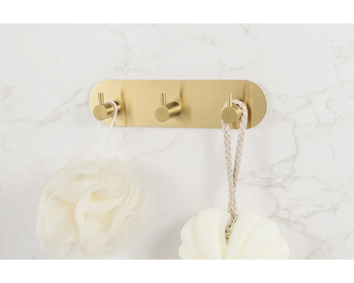 Gouden wandhaak met drie haken en badkameraccessoires.