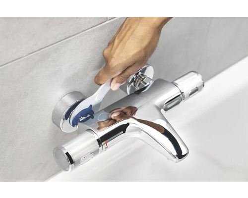 Persoon bedient een verchroomde badkraan met thermostaat.