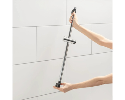 Persoon houdt een metalen douchestang vast voor een betegelde wand.