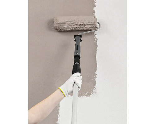 Iemand schildert een muur met een verfroller op een uitschuifbare steel.