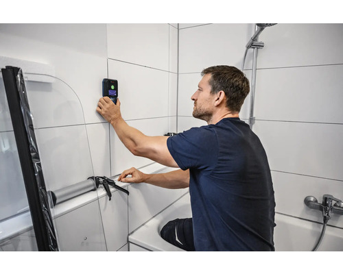 Man gebruikt wandscanner in de badkamer voor badkamerrenovatie.