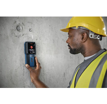Een bouwvakker gebruikt een Bosch detector op een betonnen muur
