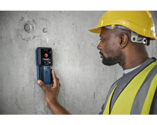 Een bouwvakker gebruikt een Bosch detector op een betonnen muur