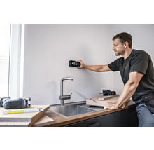 Man gebruikt een digitale detector op een muur in een keuken.