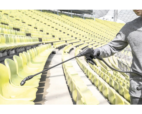 Een persoon gebruikt een spuitlans voor het reinigen van stoelen in een stadion.