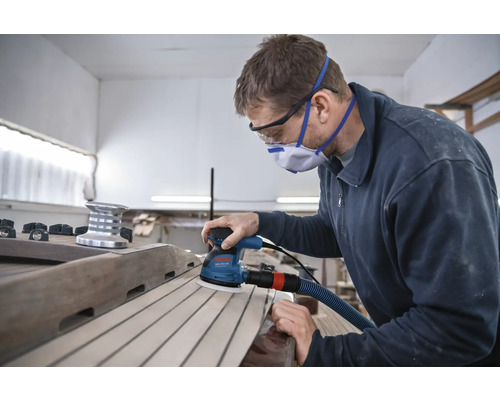 Man schuurt houten dek met een excentrische schuurmachine