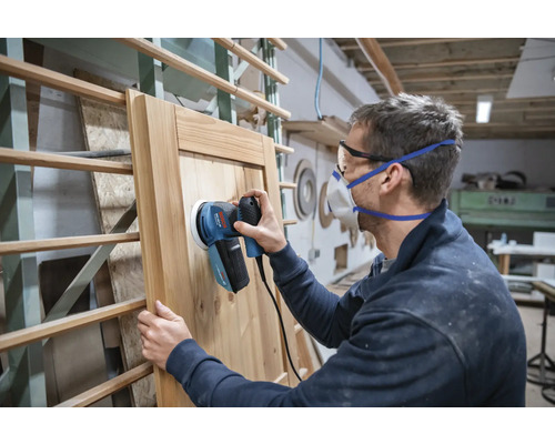 Man schuurt houten deur met excentrische schuurmachine