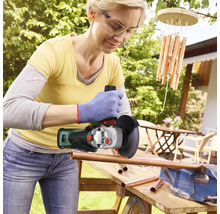 Vrouw snijdt koperen buizen in de tuin met een haakse slijper.